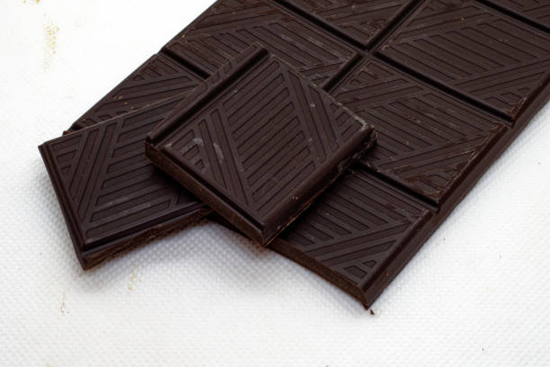 A bar of dark chocolate, opened, cropped against a white background